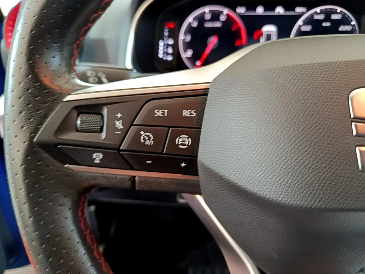 Gros plan sur la partie gauche du volant en cuir noir perforé du SEAT Arona 2022, avec commandes multifonctions visibles.