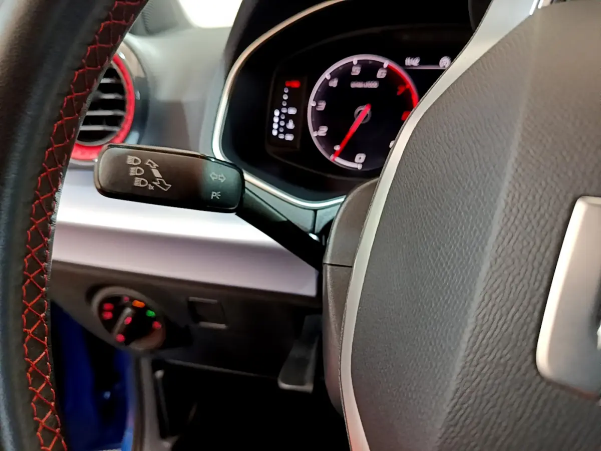 Gros plan sur le volant et le combiné d'instruments digital du SEAT Arona bleu, avec détails du commodo et coutures rouges.