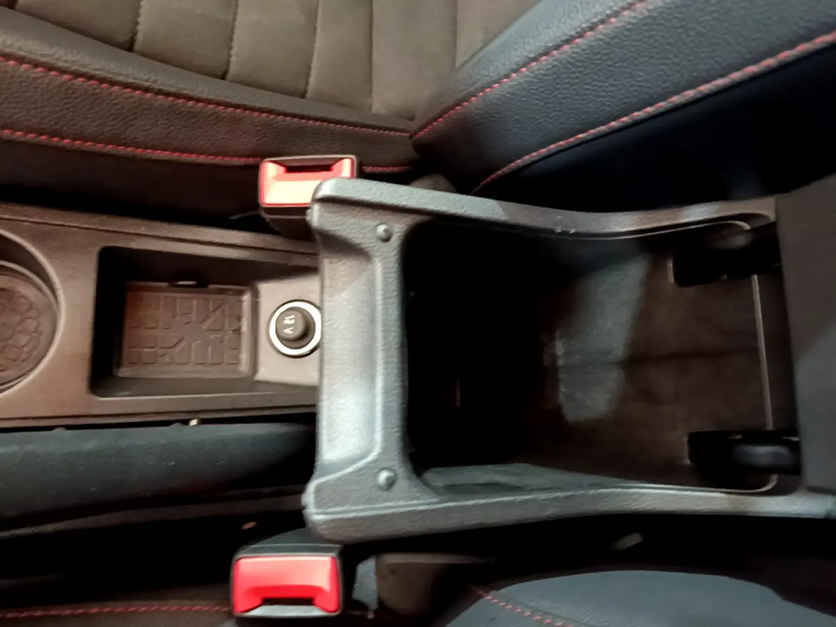 Vue plongeante sur le rangement central ouvert et les sièges noirs avec surpiqûres rouges d’un SEAT Arona bleu 2022.