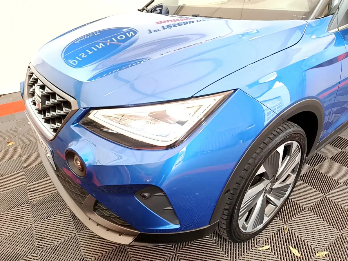 Vue 3/4 avant droit d'un SEAT Arona bleu 2022 avec phares LED et jantes alliage distinctives.