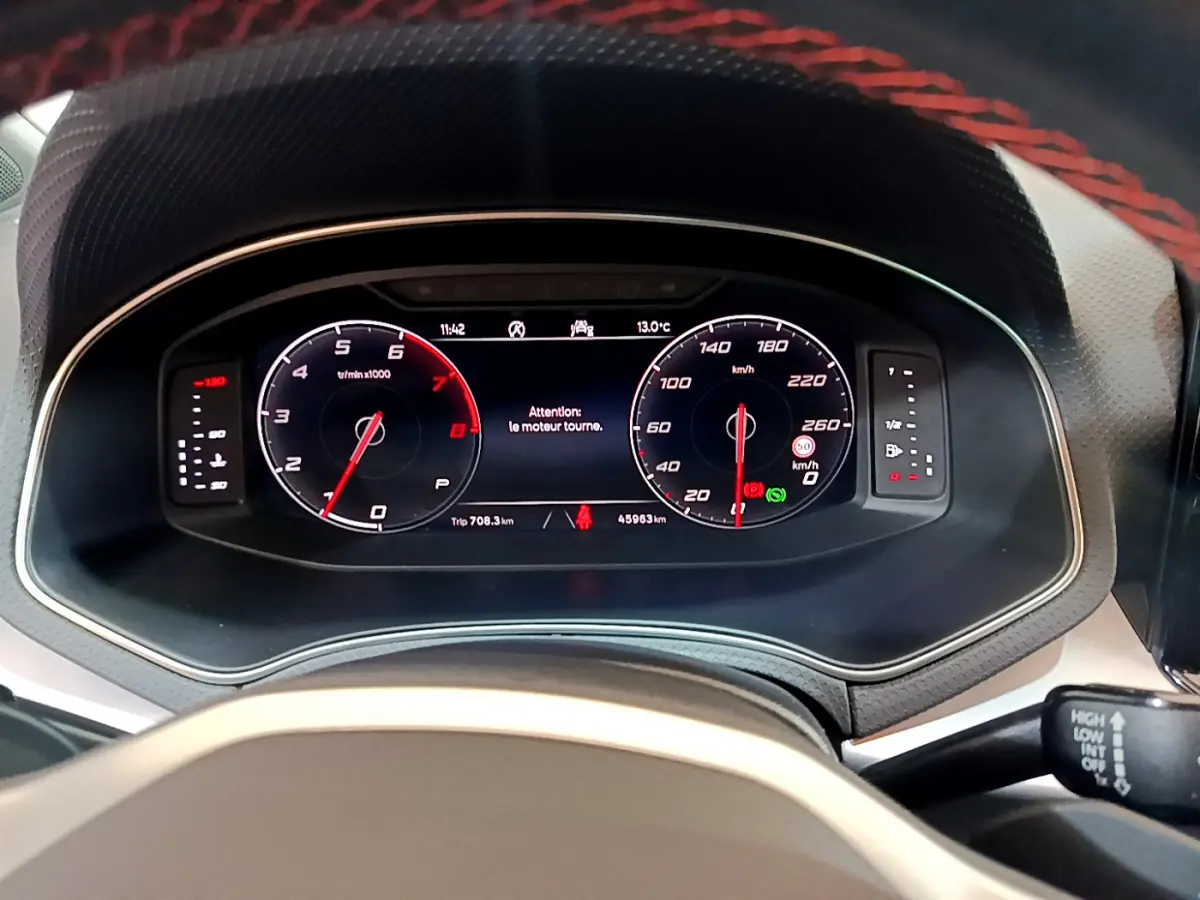 Vue rapprochée du tableau de bord digital du SEAT Arona 2022, affichage vitesse et compte-tours avec message moteur.