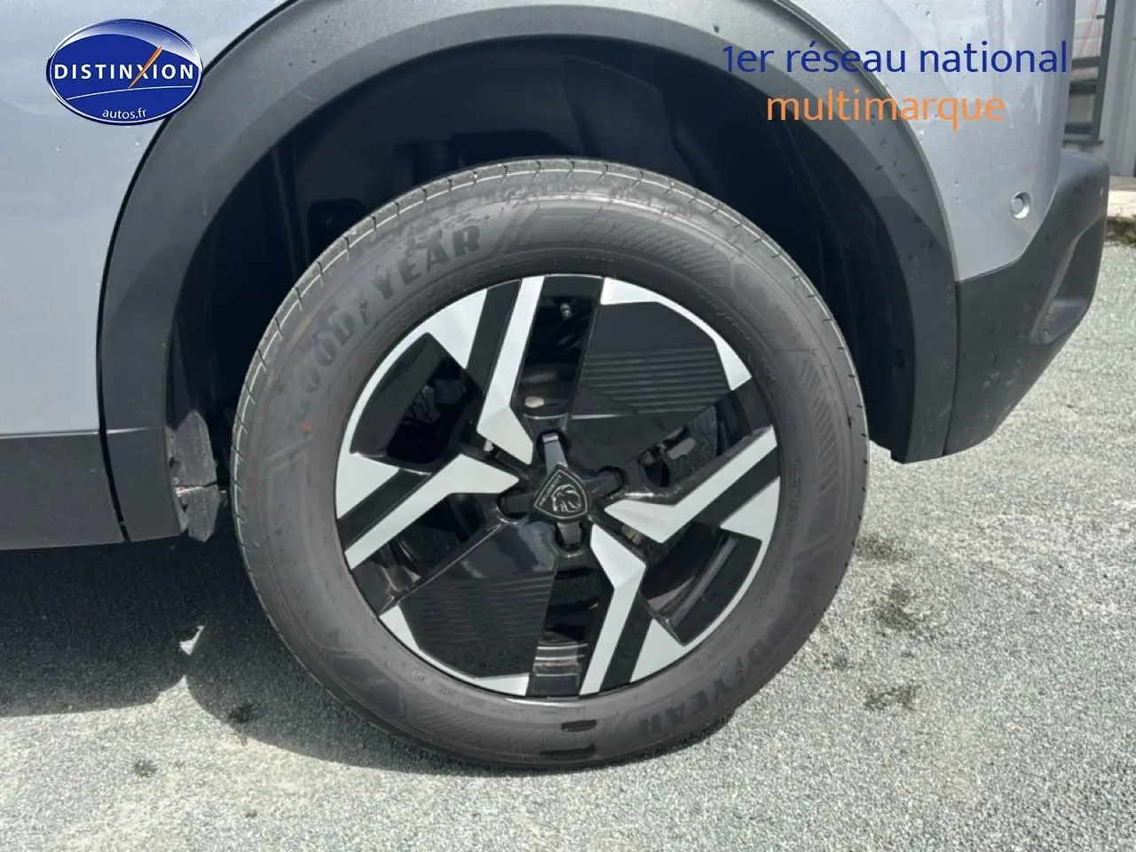 Gros plan sur la roue avant droite du Peugeot 2008 gris artense avec jante alu bicolore et logo Peugeot central.
