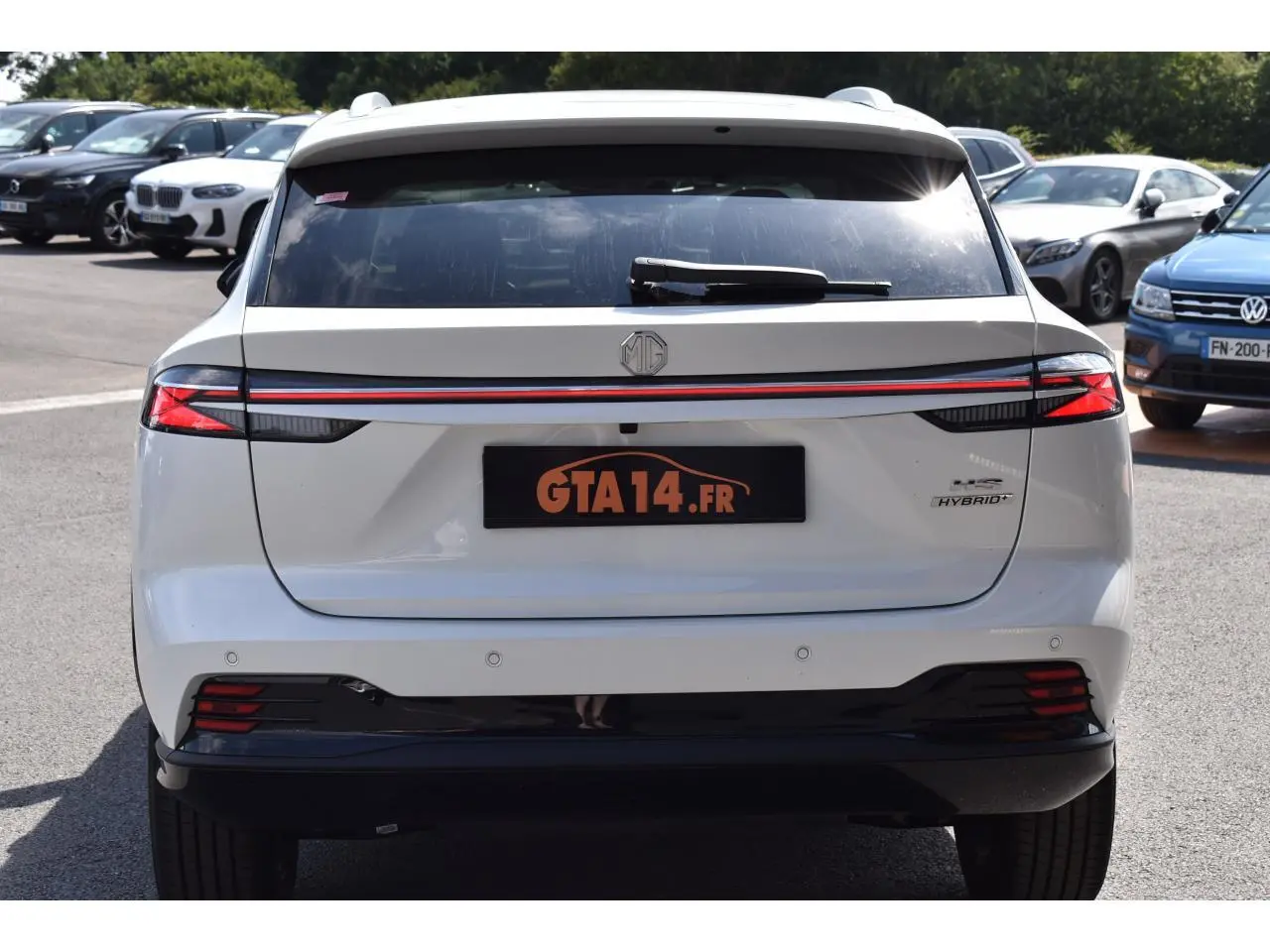 Vue arrière d'un MG MOTOR EHS blanc 1.5 Hybrid+ 224 ch Luxury avec feux LED et bande lumineuse rouge continue.