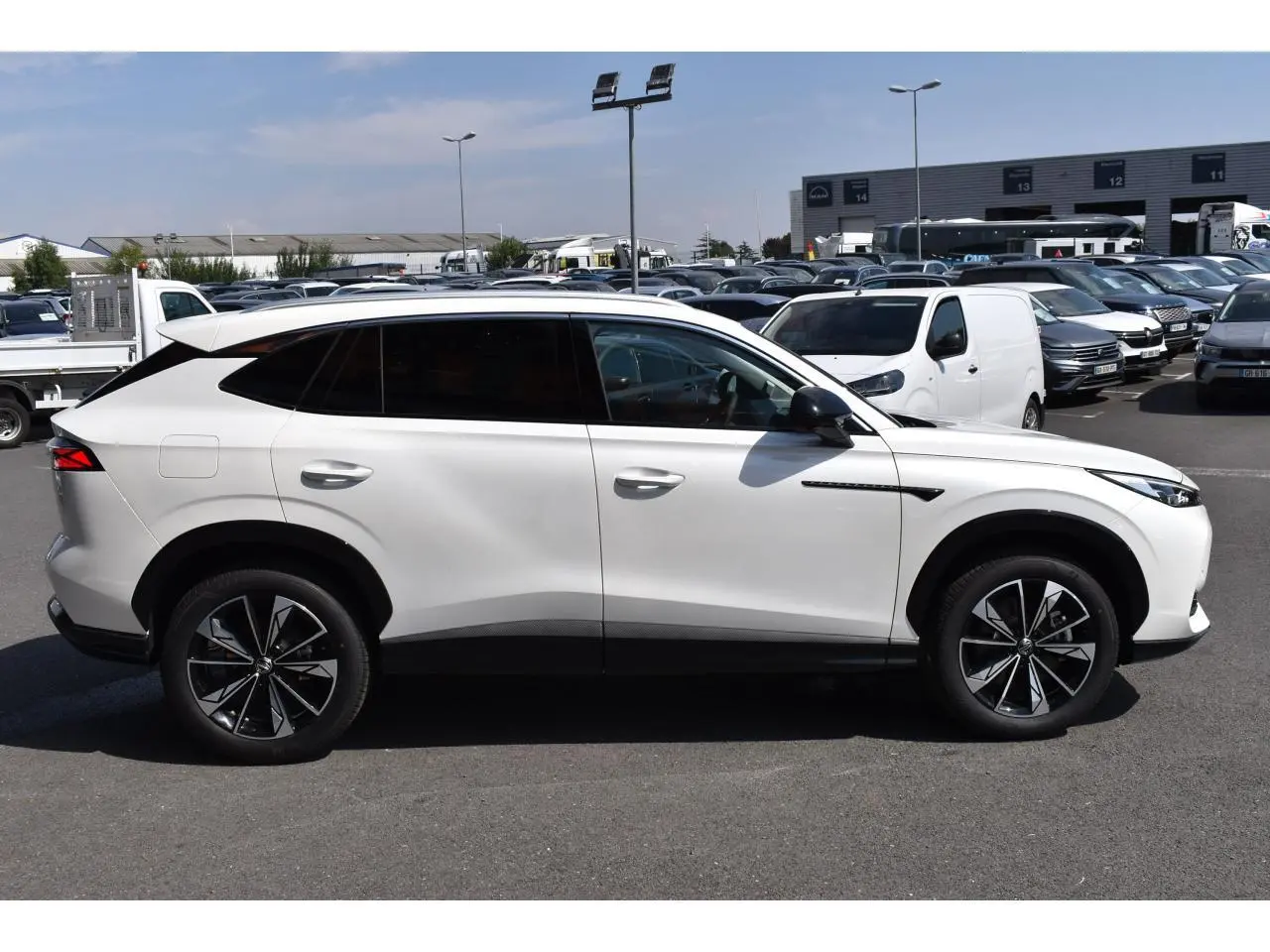 Vue de profil côté gauche du SUV blanc MG EHS 1.5 Hybrid+ Luxury 2026 avec jantes alliage noires et vitres surteintées.