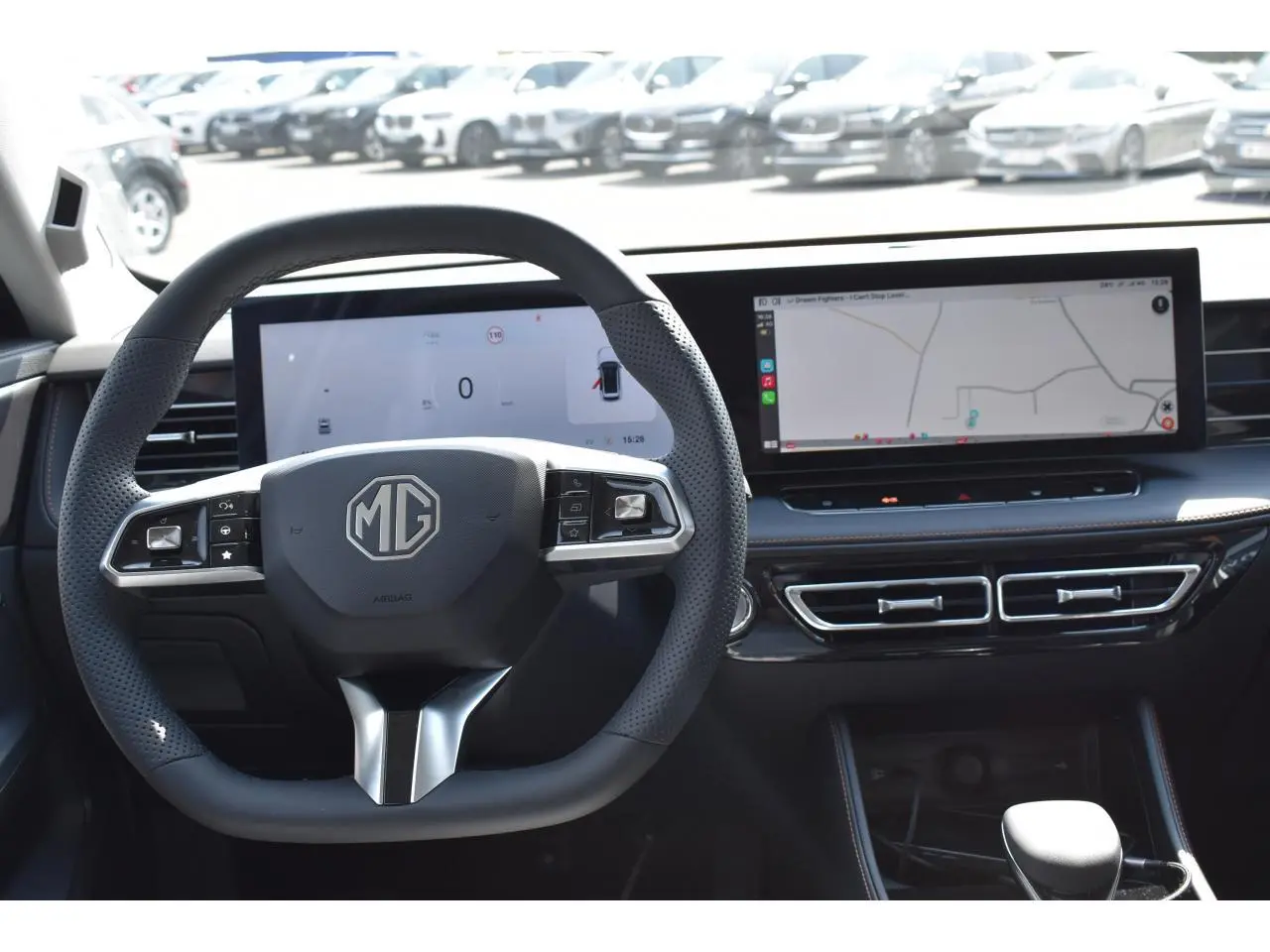 Vue intérieure centrée sur le volant noir perforé et les deux écrans numériques larges du MG Motor EHS blanc 2026.