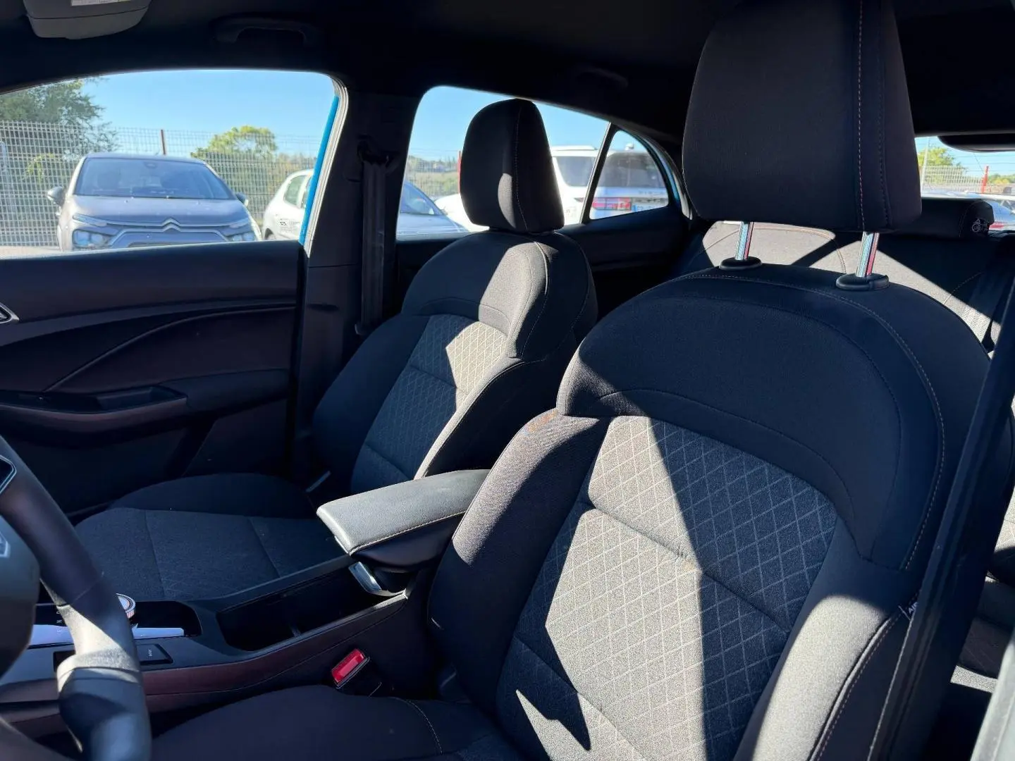 Vue intérieure côté droit du MG3 1.5 Hybrid+ 195ch Comfort 2025, sièges tissu noir avec accoudoir central.