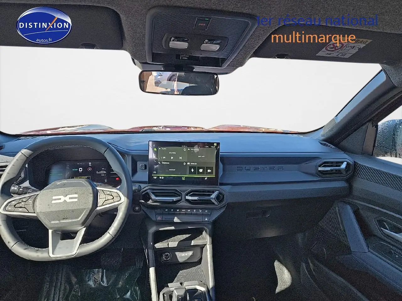 Vue intérieure avant du tableau de bord noir du Dacia Duster 2025 avec écran tactile et volant multifonction.