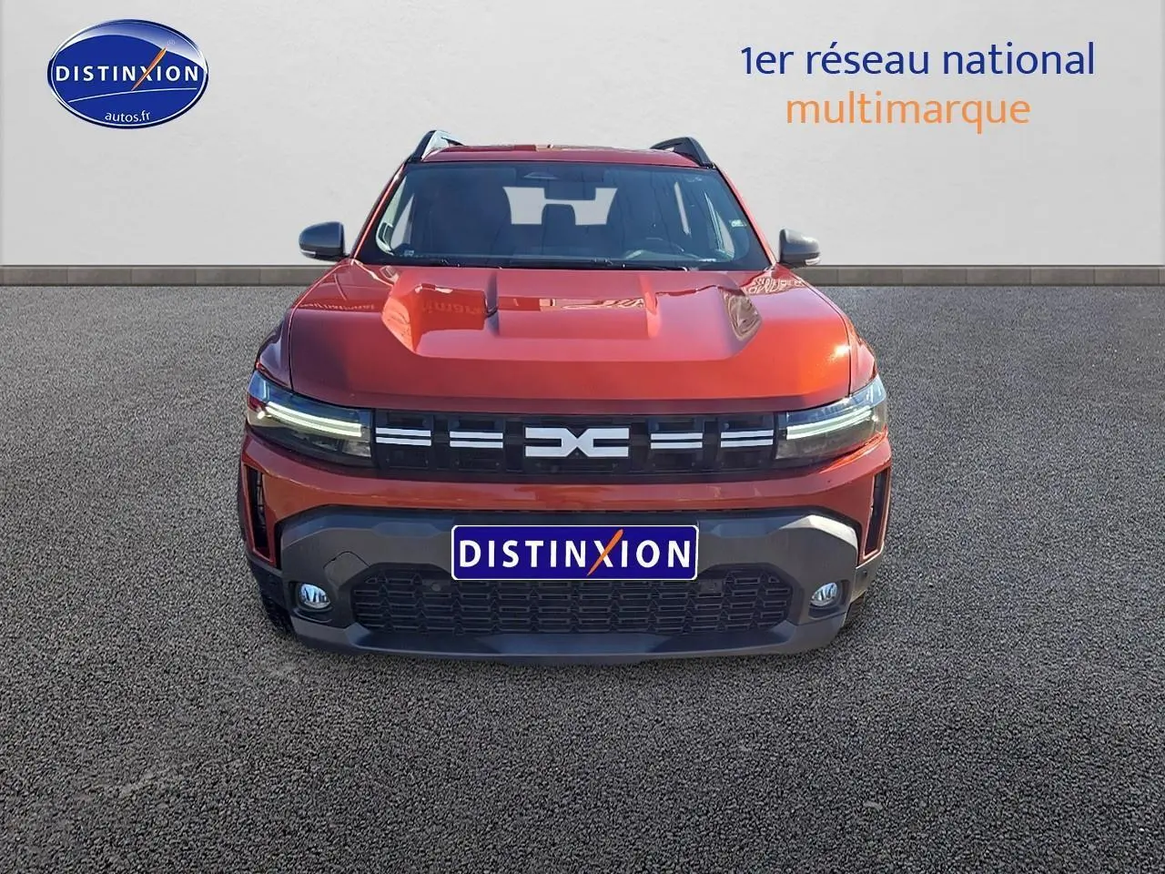 Vue frontale du Dacia Duster 2025 brun terracotta avec calandre noire et phares LED fins allumés.