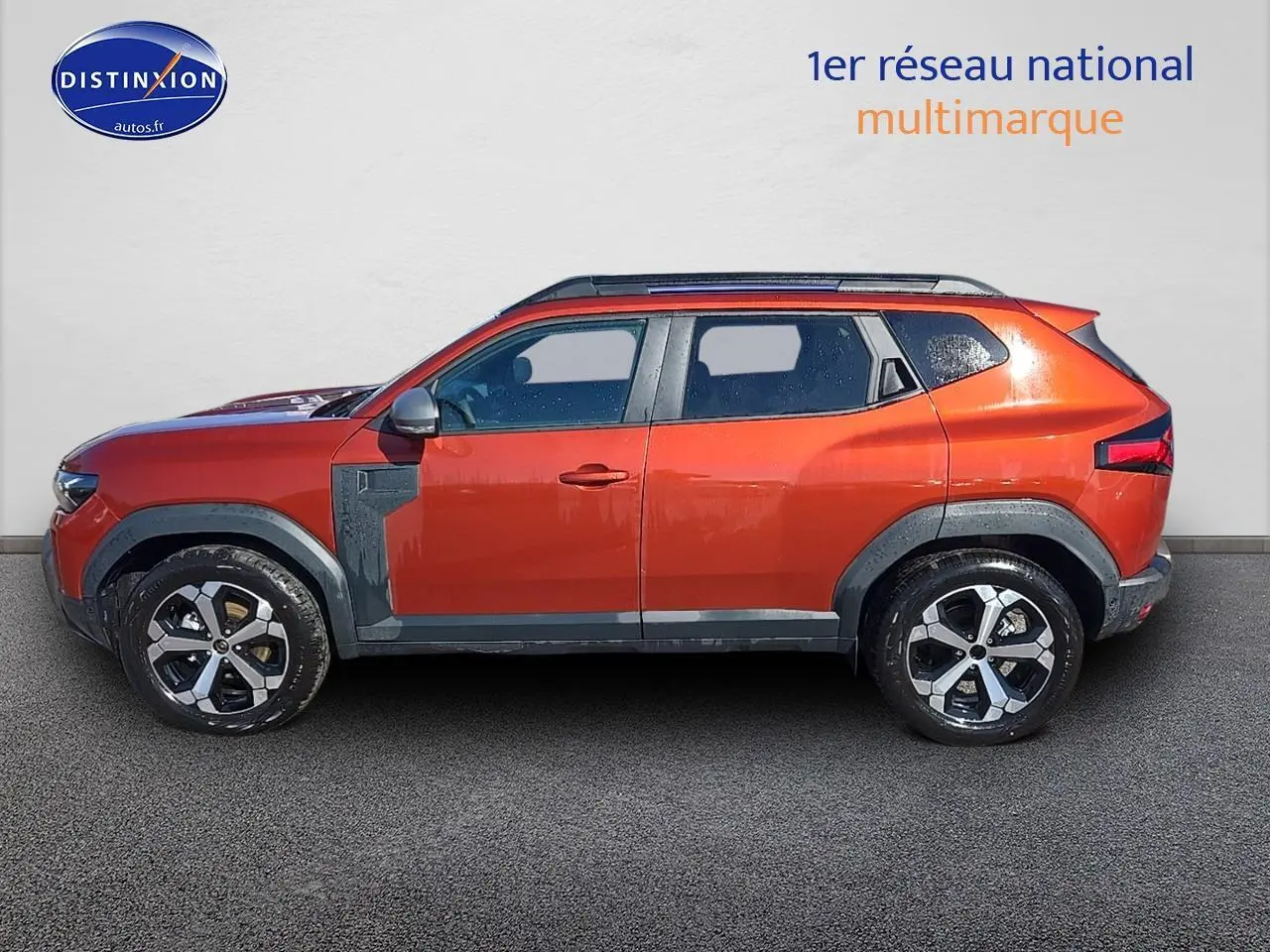 Profil côté gauche du Dacia Duster 2025 brun terracotta avec barres de toit et jantes alu distinctives.