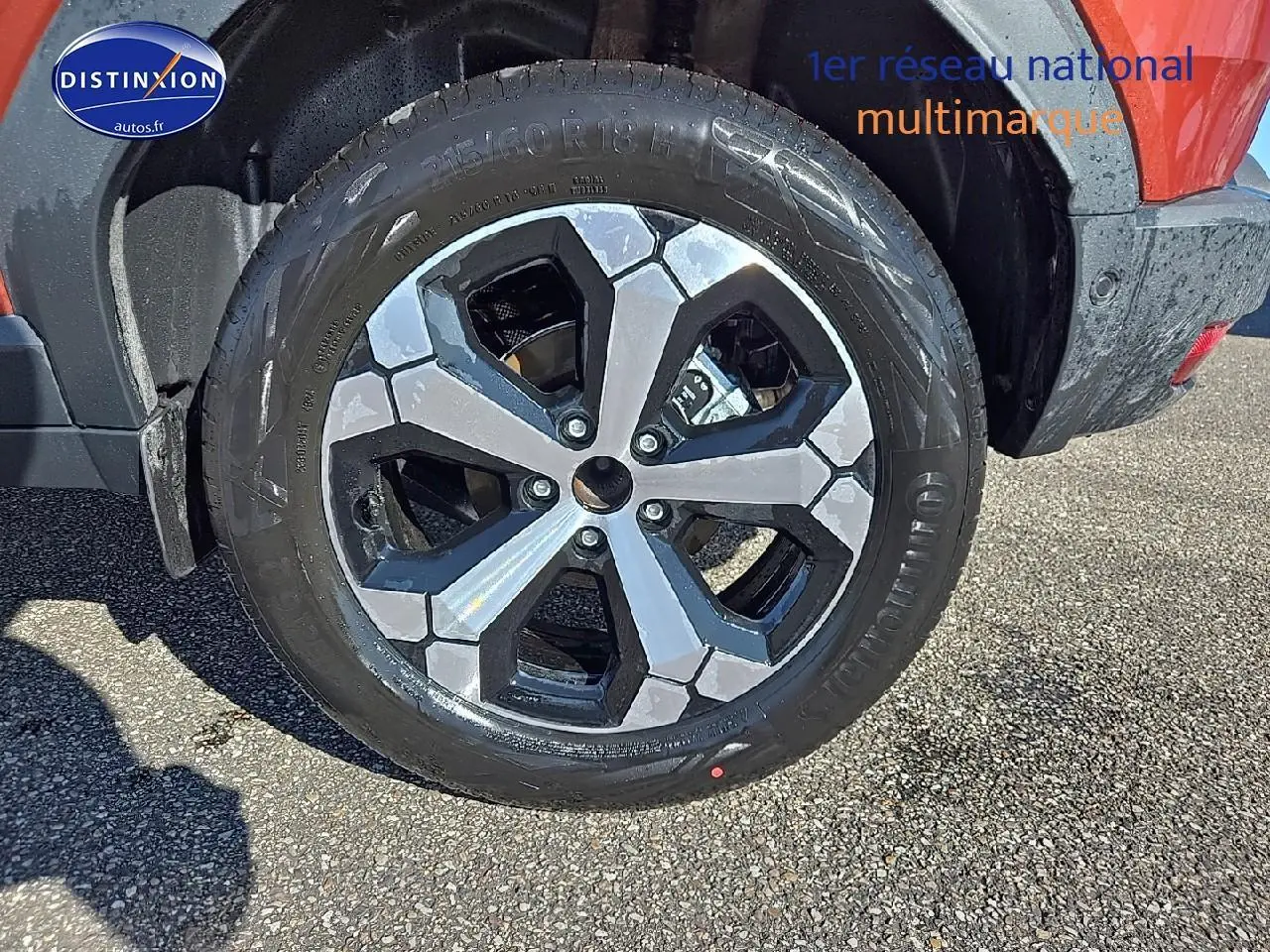 Gros plan sur la jante alu noire et argent du Dacia Duster brun terracotta, côté arrière droit du véhicule.