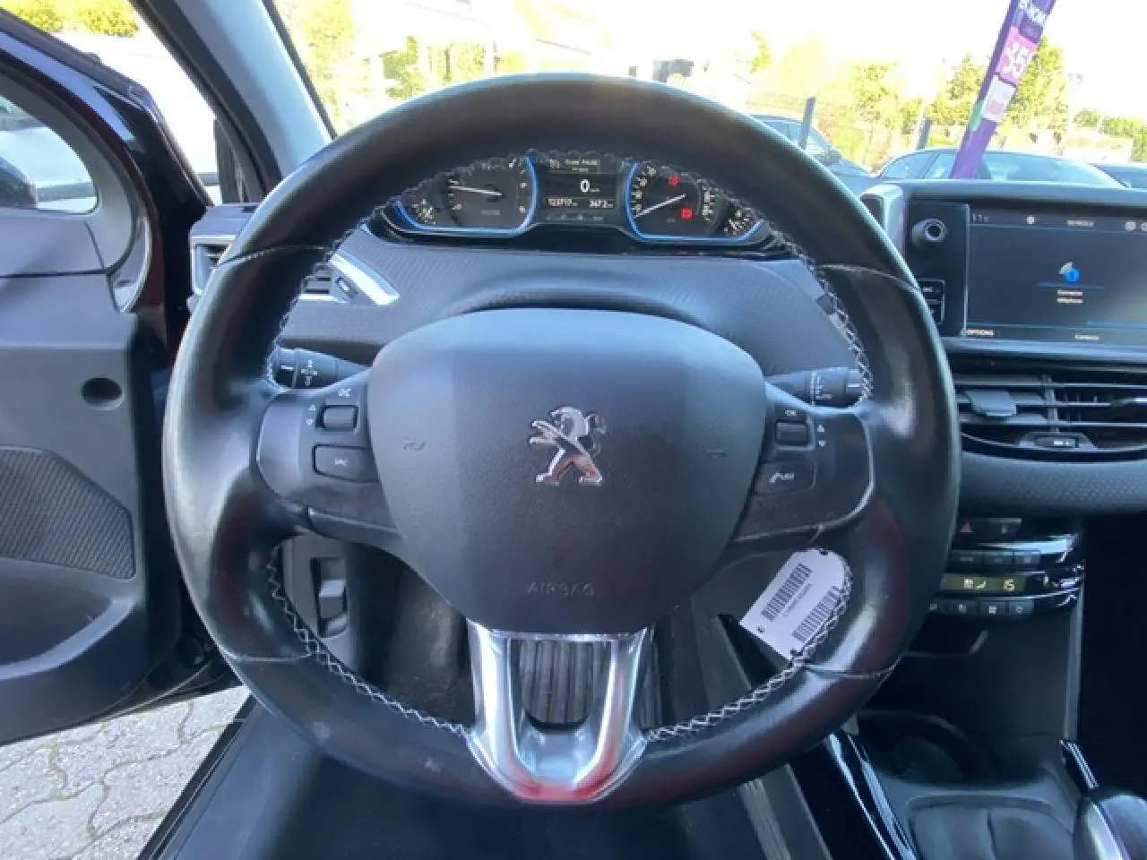 Vue rapprochée du volant cuir noir du Peugeot 2008 2019 avec tableau de bord et écran tactile visible.