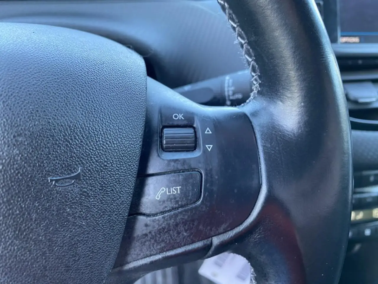 Gros plan sur les commandes gauche du volant noir du Peugeot 2008 2019, avec bouton OK et fonction liste d'appels.