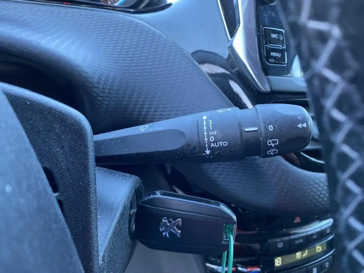 Gros plan sur la commande d'essuie-glace et la clé Peugeot dans l'habitacle noir du 2008 Diesel 2019.