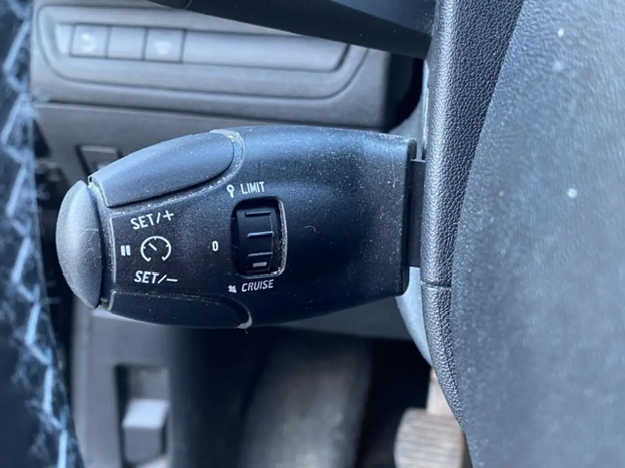 Commande du régulateur et limiteur de vitesse sur le volant d'une Peugeot 2008 noire de 2019, version diesel.