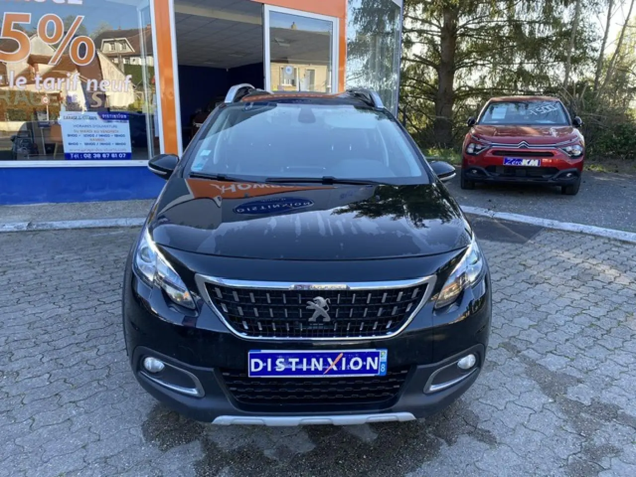 Peugeot 2008 noir métallisé vue de face, avec calandre chromée et plaques d'immatriculation Distinxion visibles.