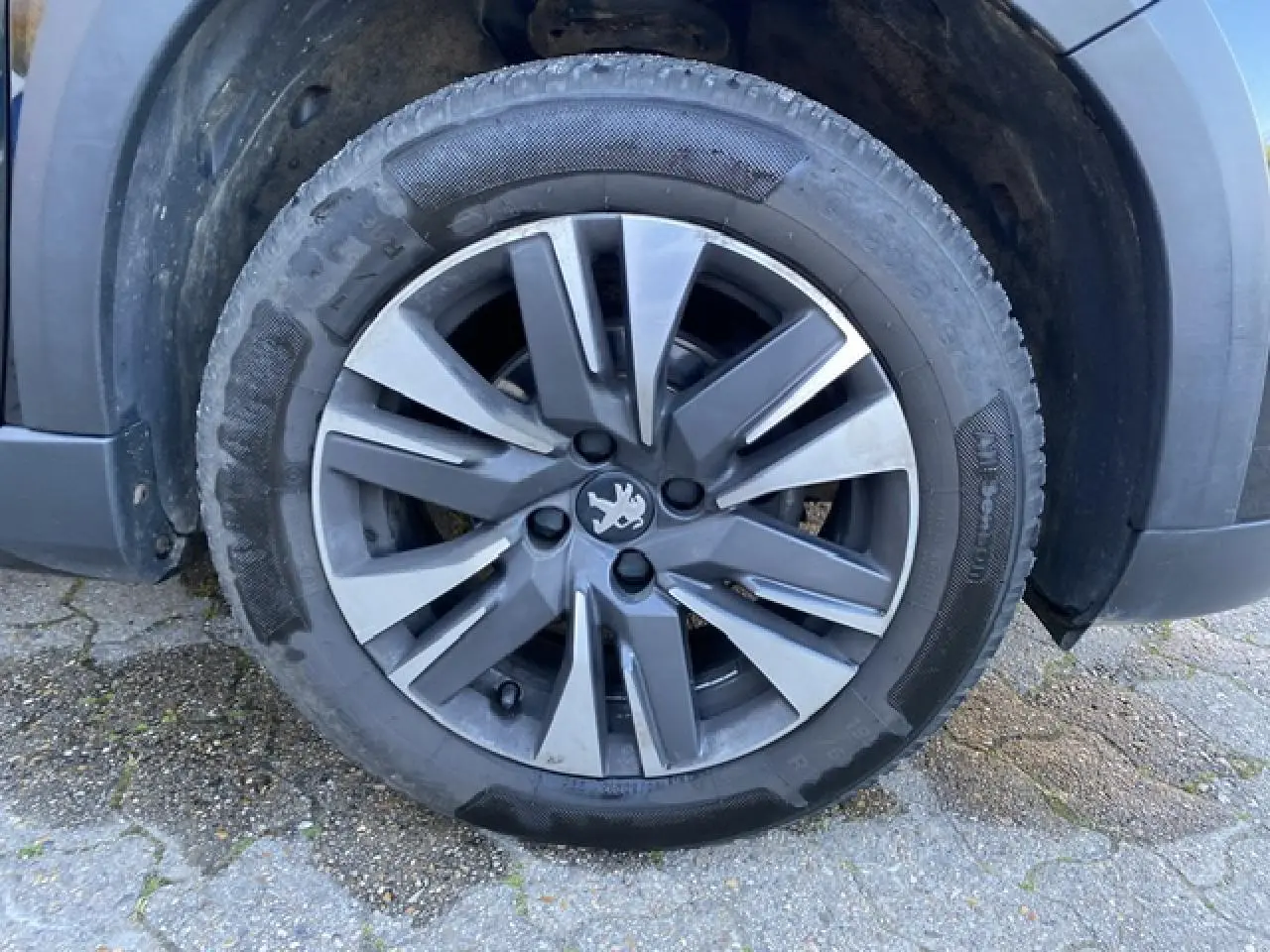 Gros plan sur la jante aluminium 16 pouces diamantée Aquila gris Storm du côté avant droit d'un Peugeot 2008 noir 2019.