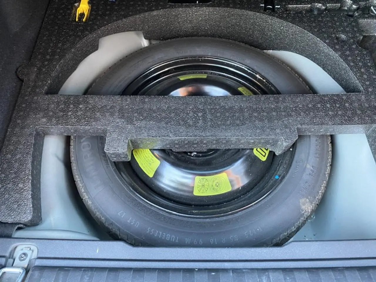 Roue de secours noire logée dans le coffre d'un Peugeot 2008 2019 finition Allure diesel noir.