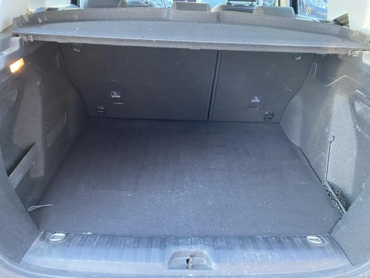 Coffre spacieux et propre du Peugeot 2008 noir, vue intérieure arrière avec cache-bagages relevé.