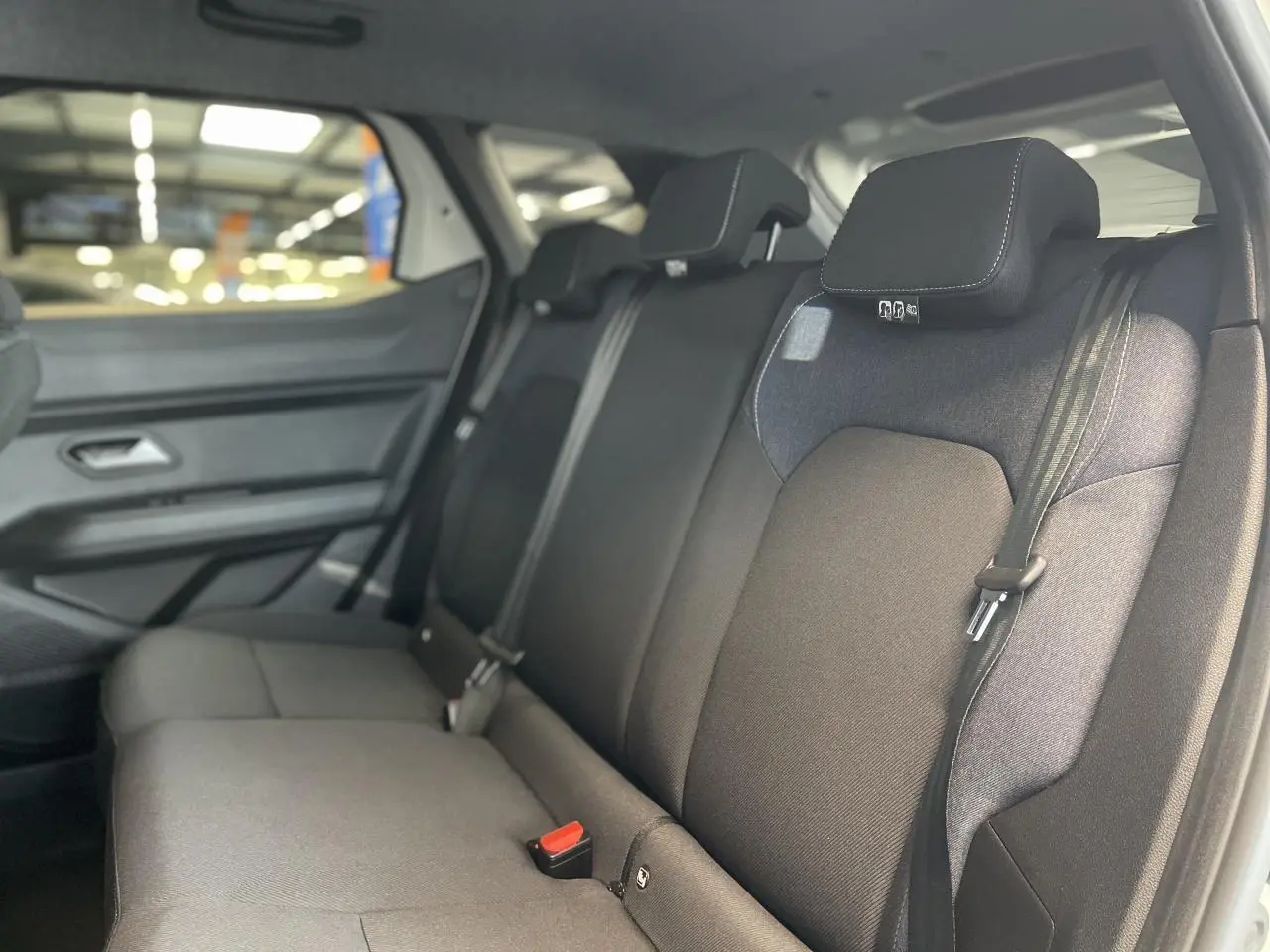 Vue intérieure côté droit sur la banquette arrière noire du Dacia Duster 2025, finition Denim avec ceintures de sécurité.