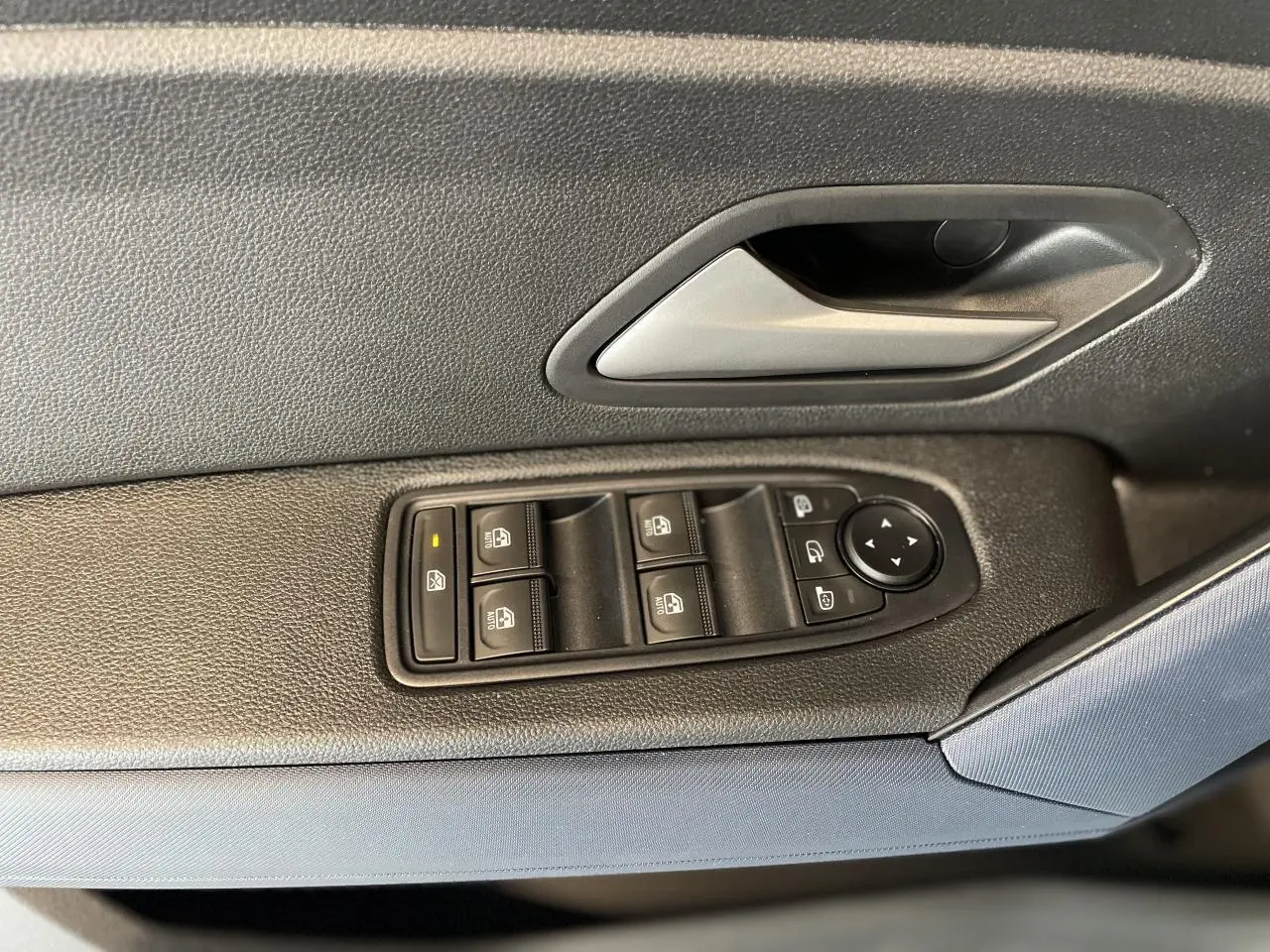 Poignée intérieure et panneau de commandes des vitres côté gauche en tissu Denim Bleu sur Dacia Duster 2025.