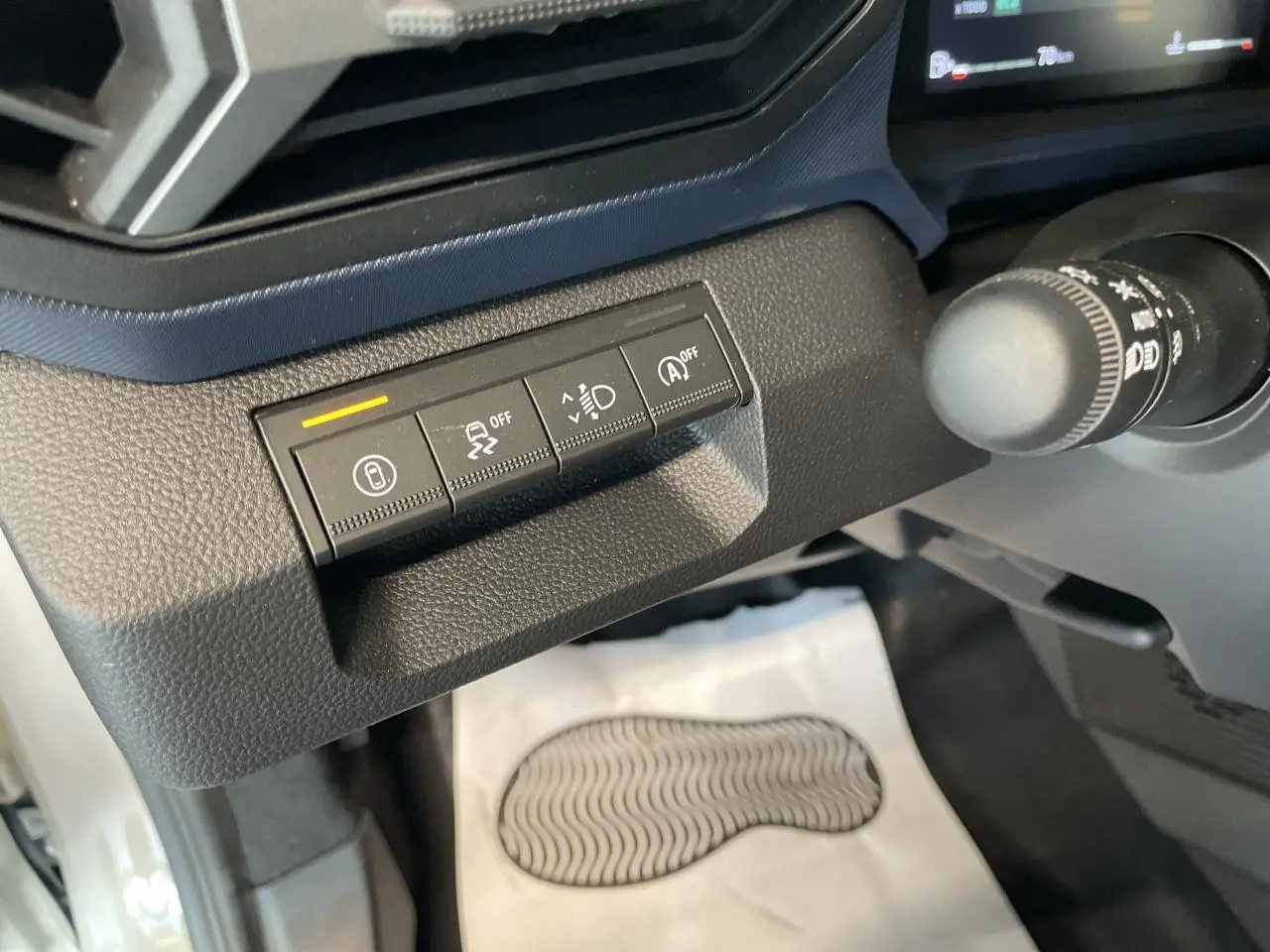 Gros plan sur les commandes de sécurité à gauche du volant dans l'habitacle du Dacia Duster beige 2025.