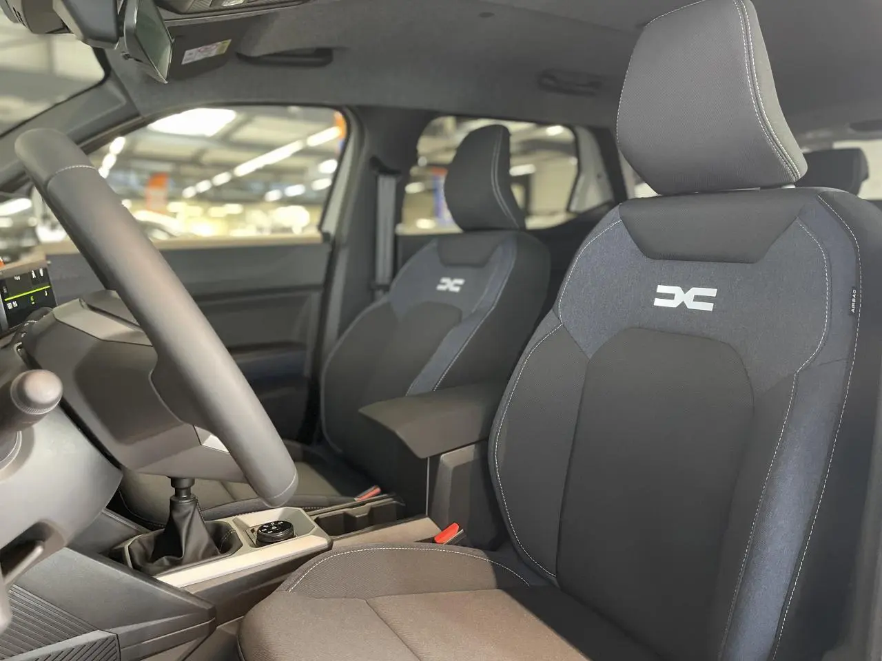 Intérieur du Dacia Duster 2025 vue côté conducteur, sièges en tissu Denim bleu avec logo Dacia brodé.