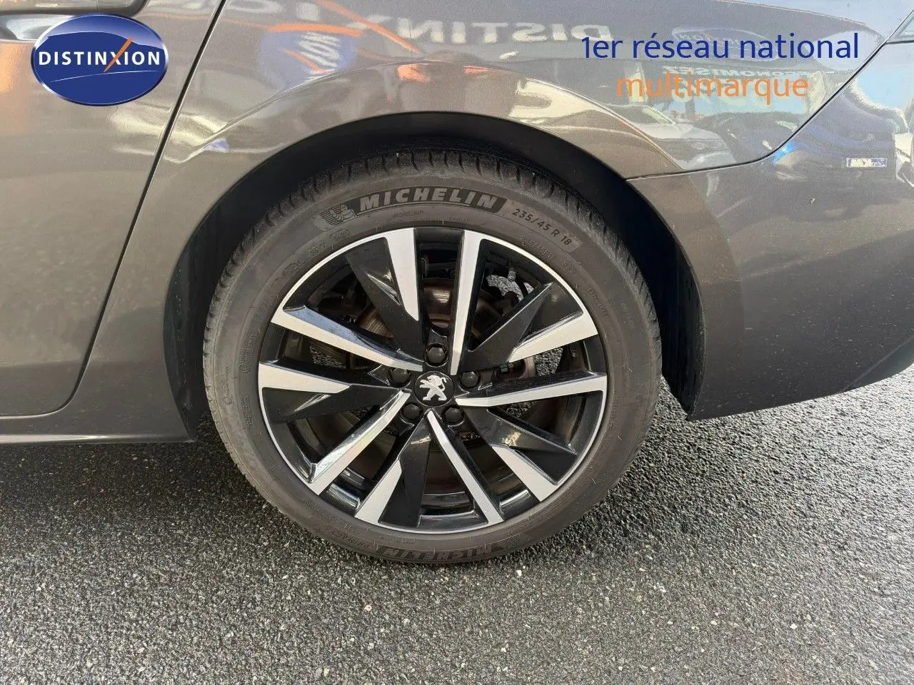 Gros plan sur la roue arrière droite d'une Peugeot 508 gris platinium avec jante alliage noire et argentée.