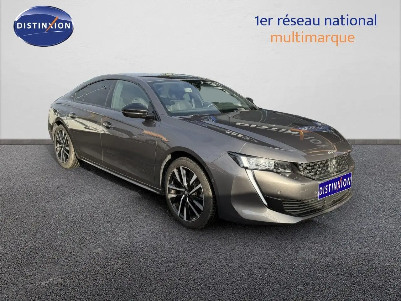 Peugeot 508 gris platinium vue 3/4 avant droit, avec jantes alliage noires et calandre distinctive.