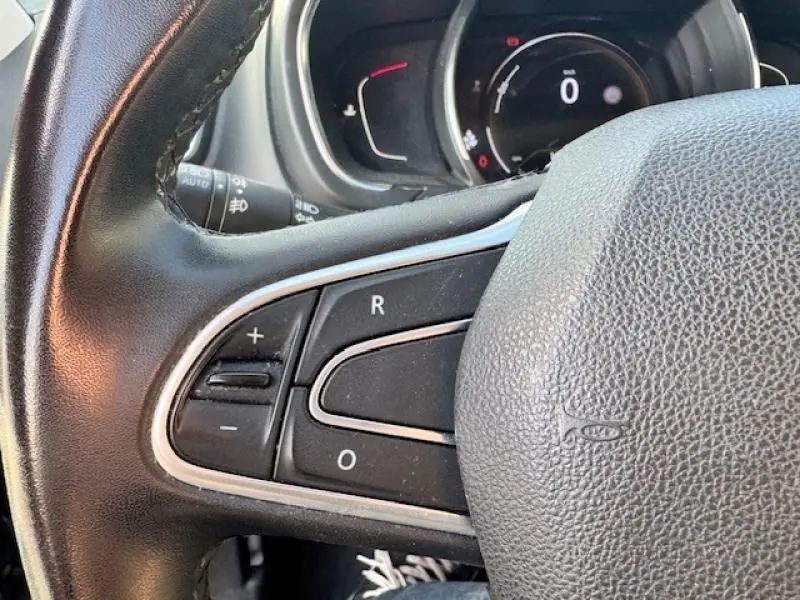 Gros plan sur le volant cuir noir du Renault Grand Scenic 2019 avec commandes de régulateur de vitesse intégrées.