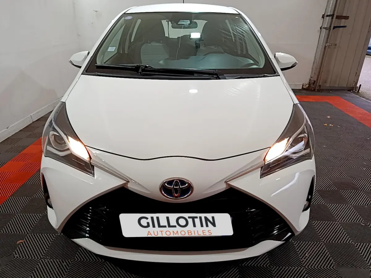 Vue avant d'une Toyota Yaris blanche 2020 avec phares allumés et calandre noire distinctive.