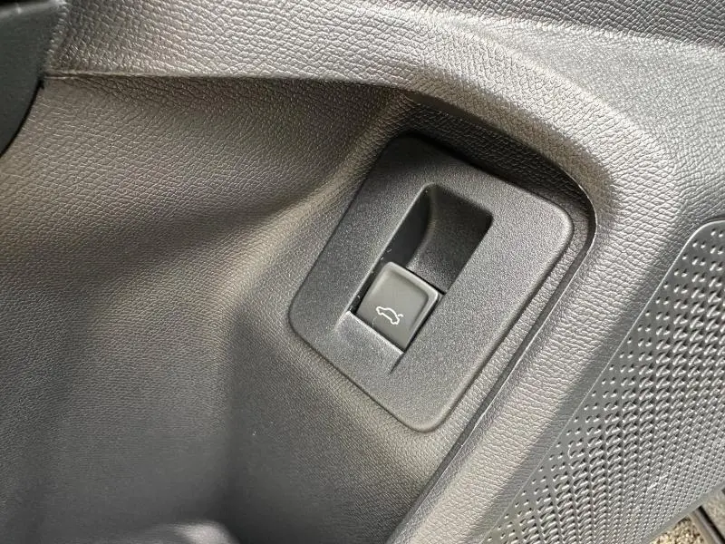 Gros plan sur le bouton d'ouverture du coffre noir dans l'habitacle du CUPRA Formentor Gris Graphène.