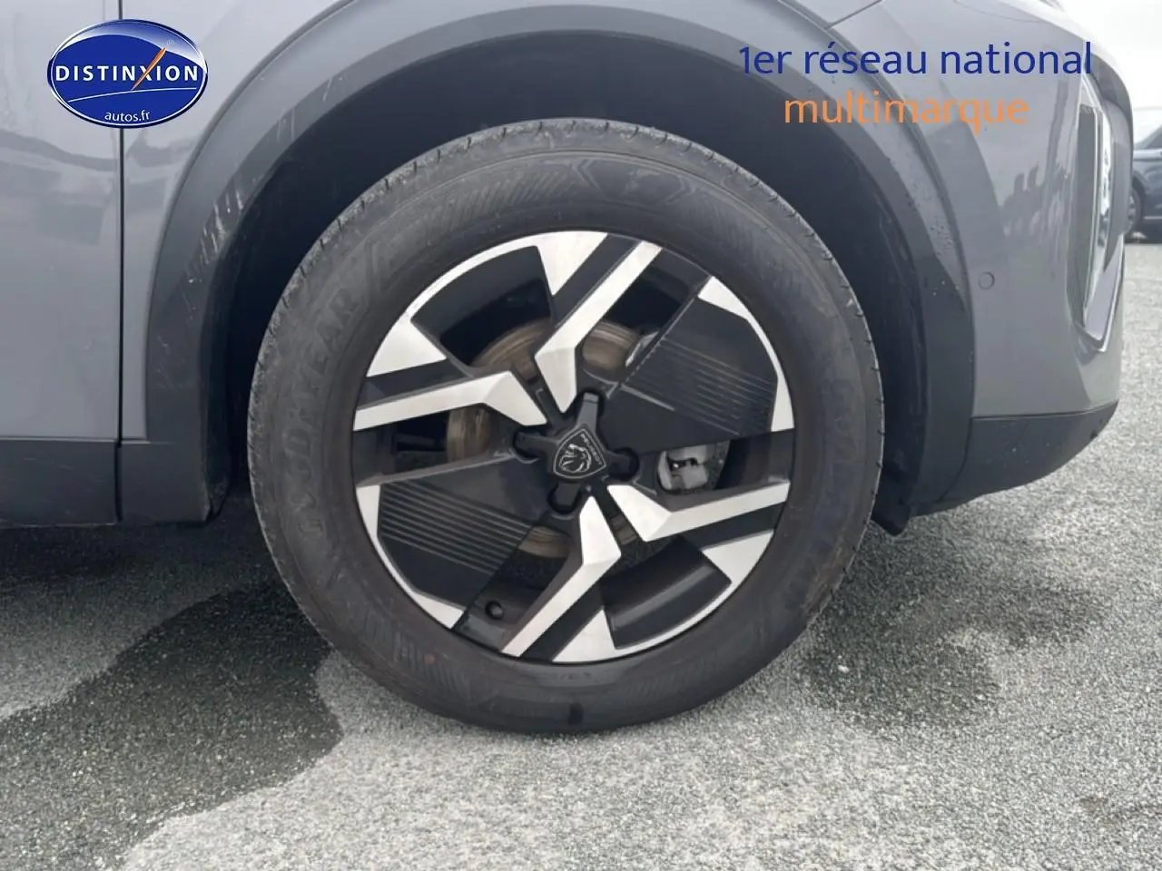 Gros plan sur la roue avant droite d'un Peugeot 2008 gris sélénite avec jante alu au design moderne.