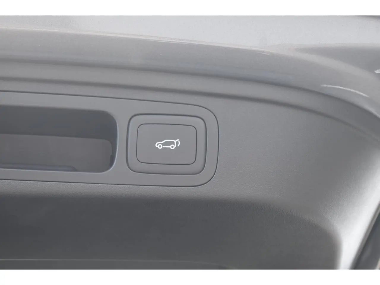Bouton de hayon électrique avec pictogramme blanc, situé à l'intérieur du coffre d'un MG Motor EHS gris.