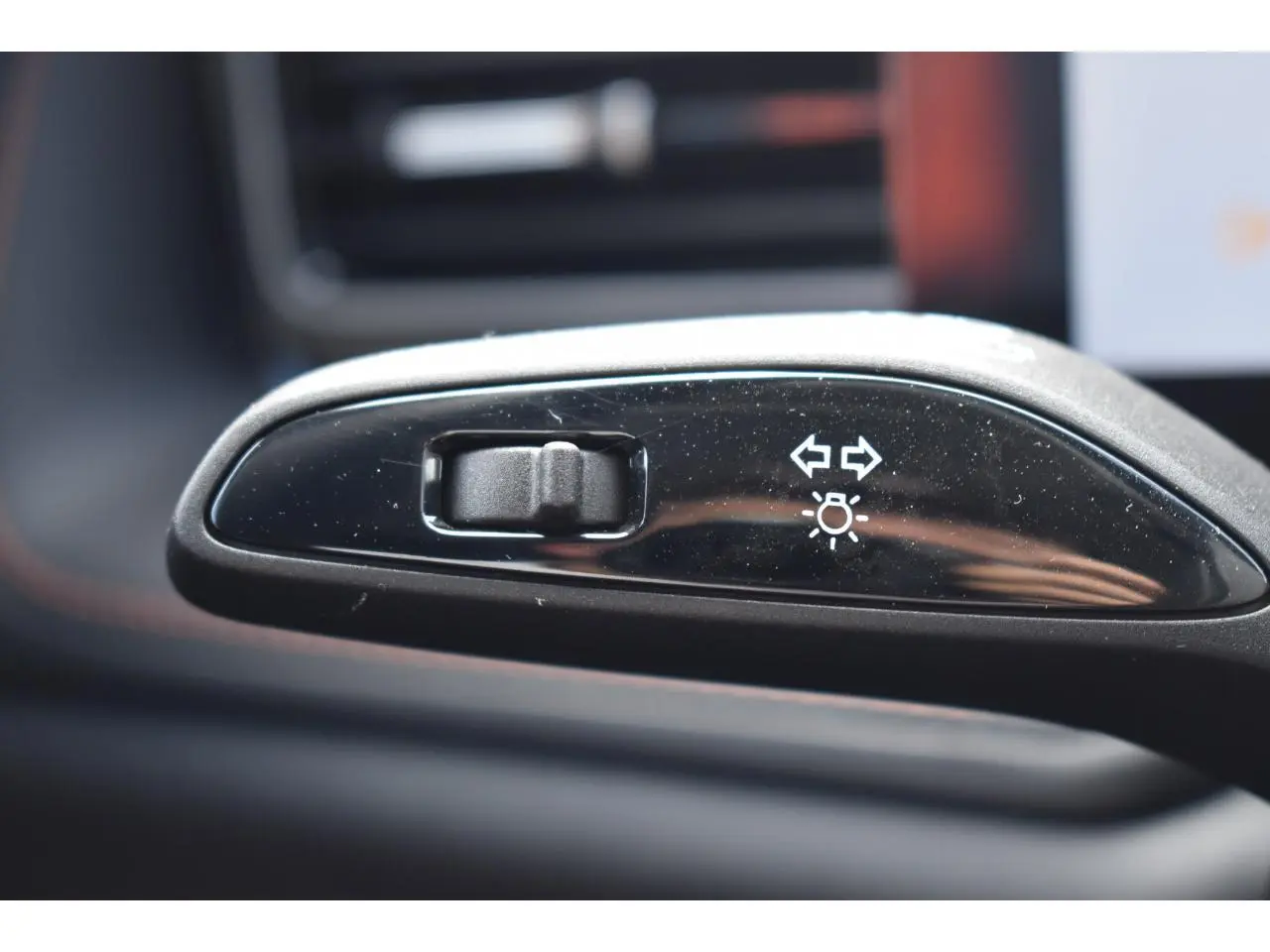 Gros plan sur le bouton de réglage des clignotants et feux, intérieur noir brillant du MG Motor EHS gris.