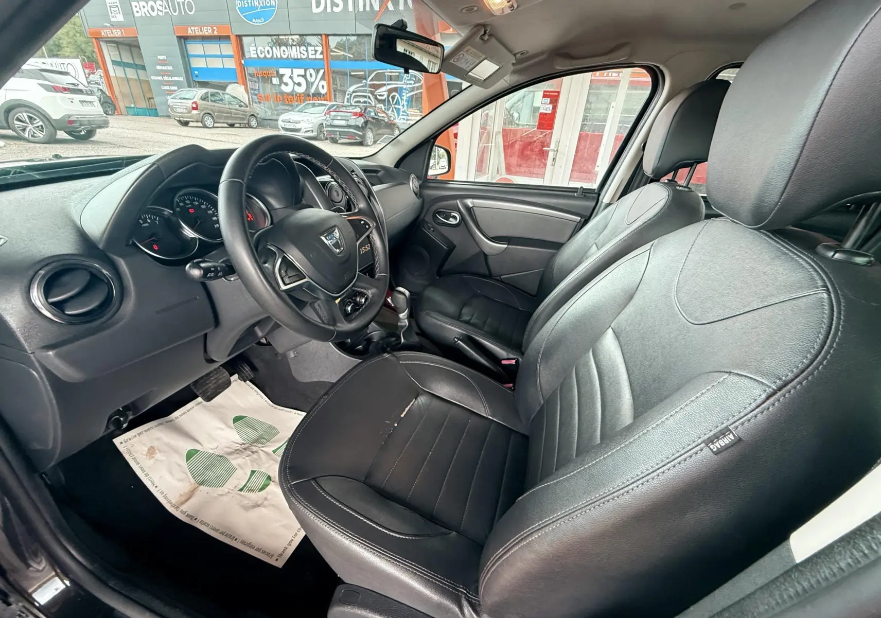 Intérieur avant du Dacia Duster 2017 noir métal, sièges cuir noir et volant multifonctions visible côté conducteur.