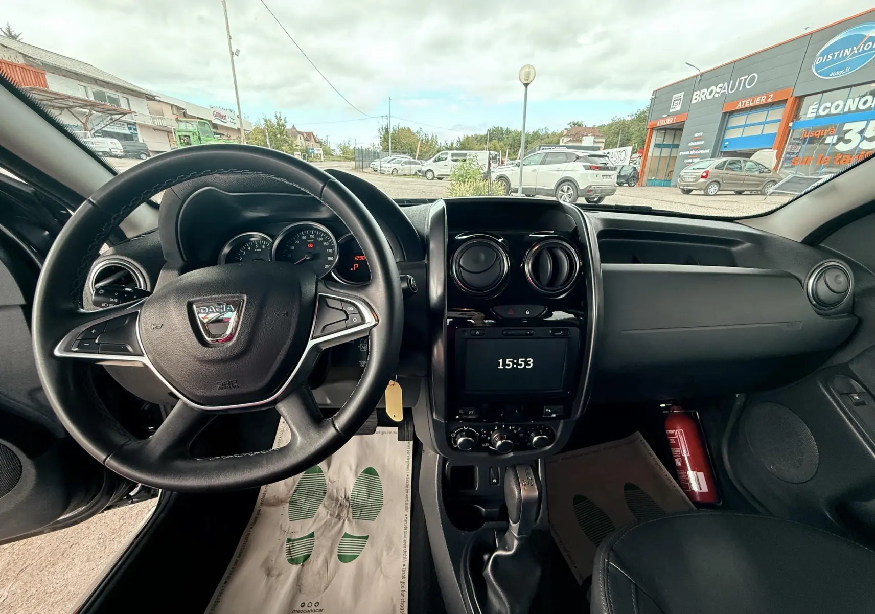 Intérieur du Dacia Duster 2017 noir métal, vue du poste de conduite avec volant, tableau de bord et écran central allumé.