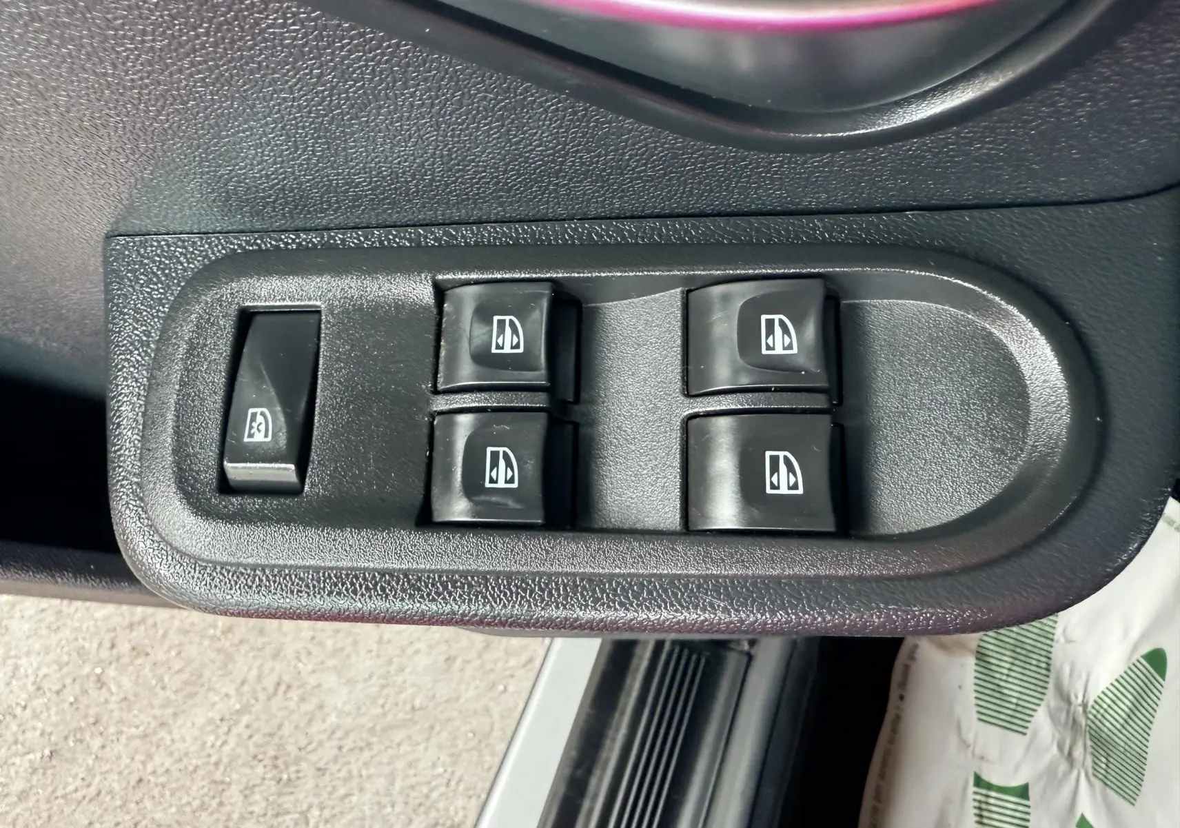 Gros plan sur les commandes des vitres électriques côté conducteur du Dacia Duster noir métal de 2017.