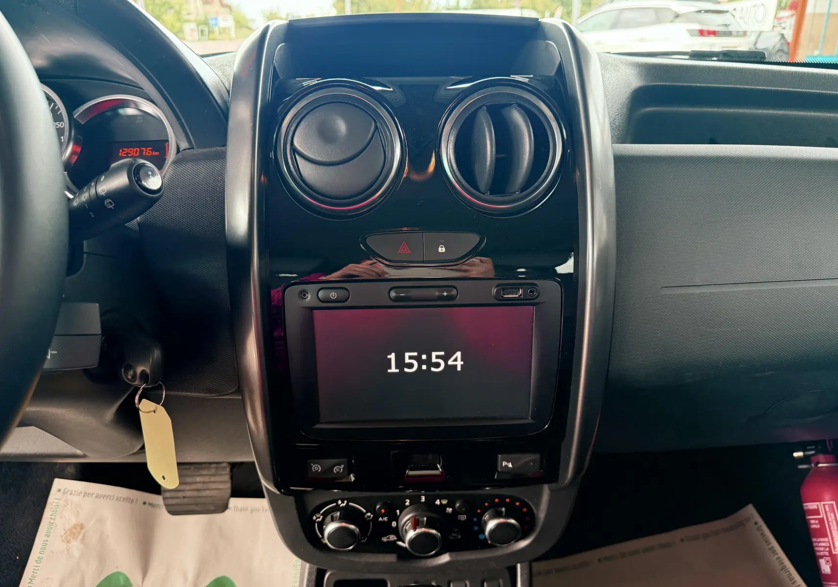 Vue rapprochée du tableau de bord noir brillant du Dacia Duster 2017, avec écran tactile affichant l'heure et commandes d'aération circulaires.