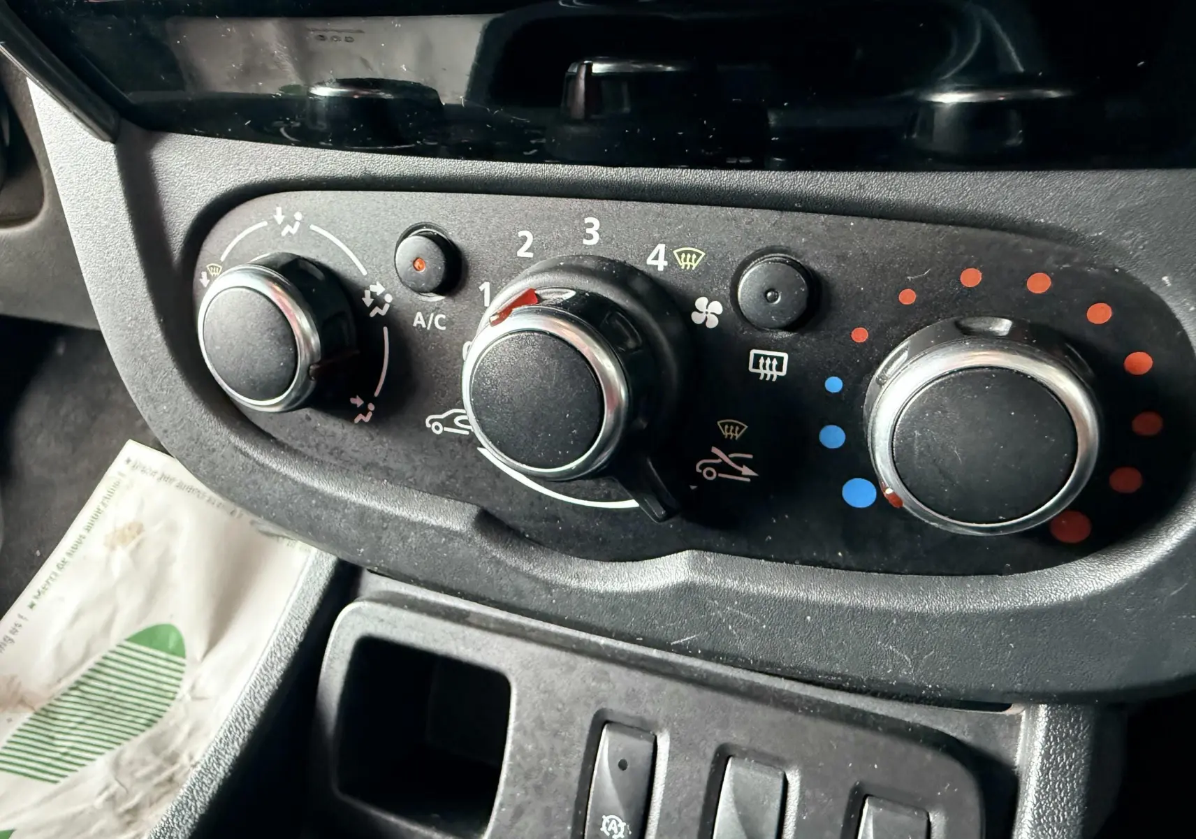 Panneau de commande de climatisation du Dacia Duster noir métal, avec trois molettes et réglages visibles.