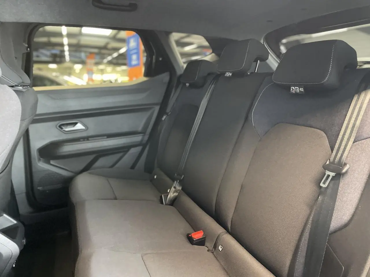Vue intérieure de la banquette arrière noire du Dacia Duster 2025 avec ceintures et appuie-têtes intégrés.