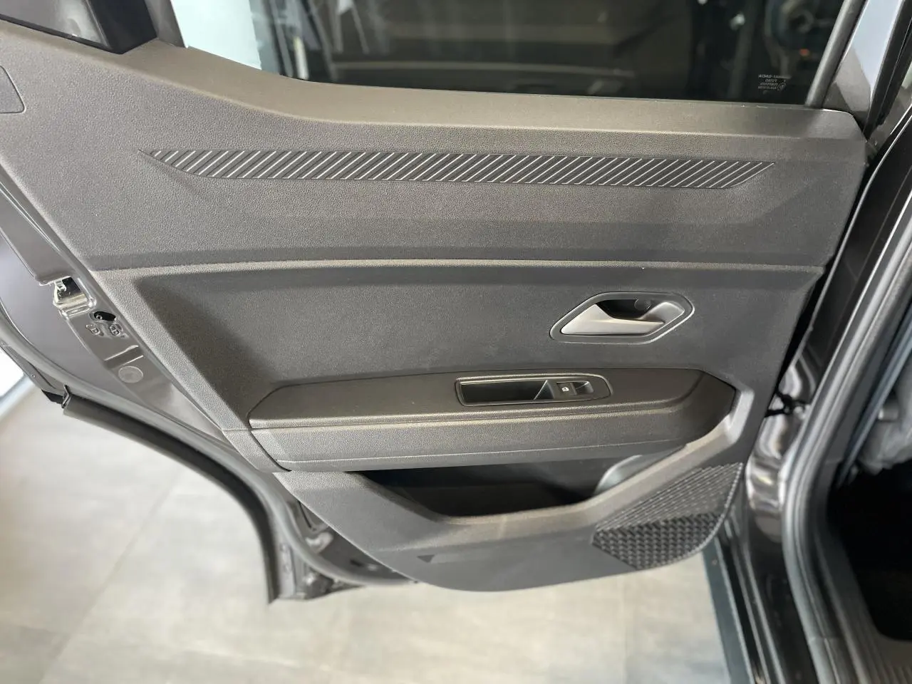 Porte arrière côté gauche noire métallisée du Dacia Duster 2025 avec poignée argentée et commande de vitre électrique.