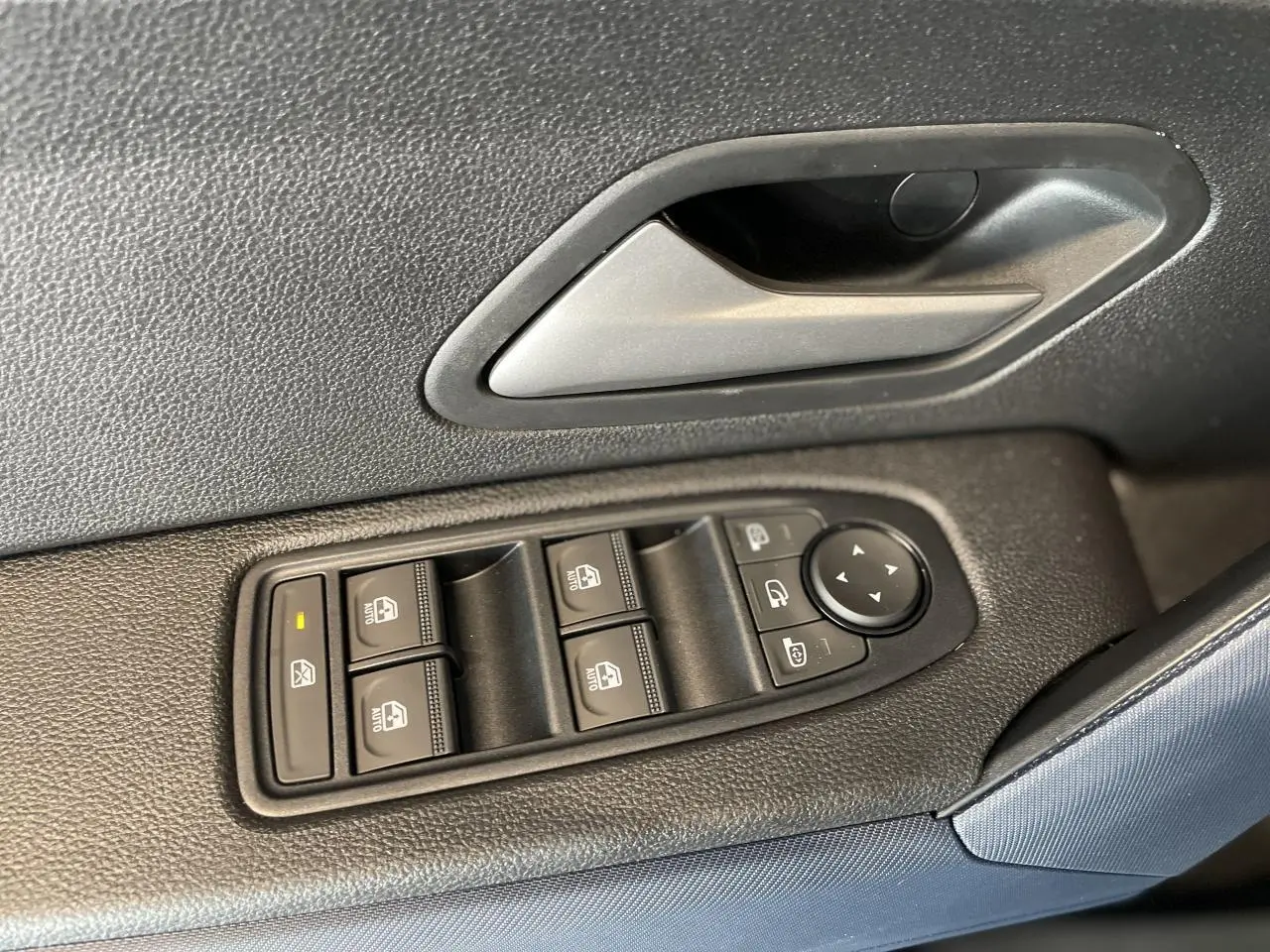 Gros plan sur la commande des vitres électriques et la poignée intérieure côté gauche du Dacia Duster 2025 finition Journey.