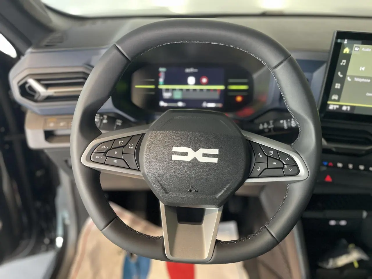 Volant noir du Dacia Duster 2025 avec commandes intégrées, tableau de bord digital et écran tactile central visible.