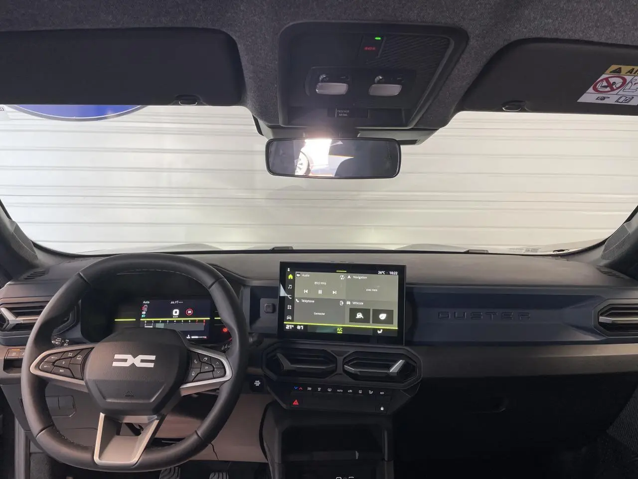 Vue frontale de l'habitacle du Dacia Duster 2025 noir métallisé, avec tableau de bord digital et écran tactile central.