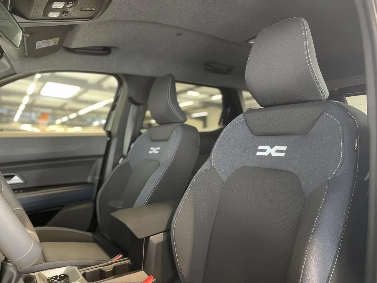 Gros plan sur les sièges avant en sellerie Denim bleu et noir du Dacia Duster 2025, avec logo DC brodé.