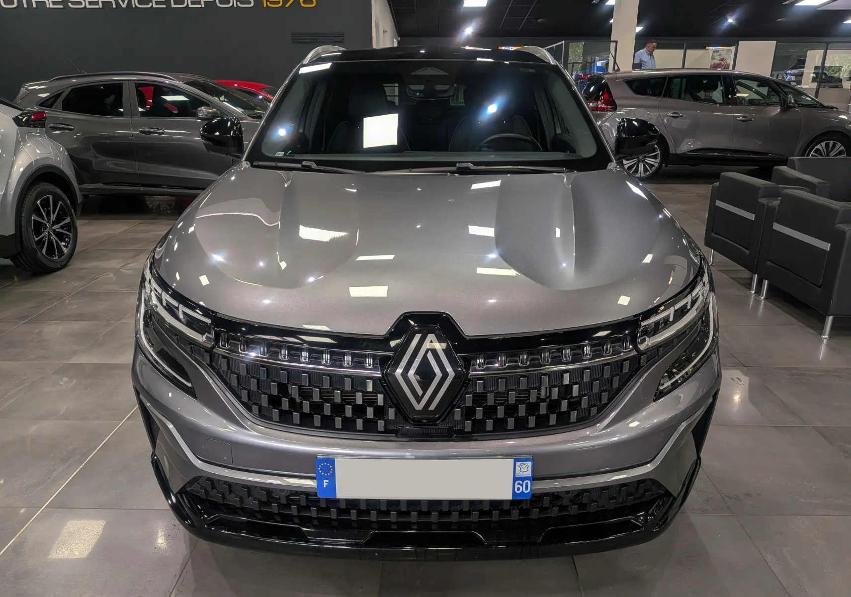 Vue frontale d'un Renault Austral E-TECH Full Hybrid gris schiste, avec calandre noire à damier et logo Renault central.