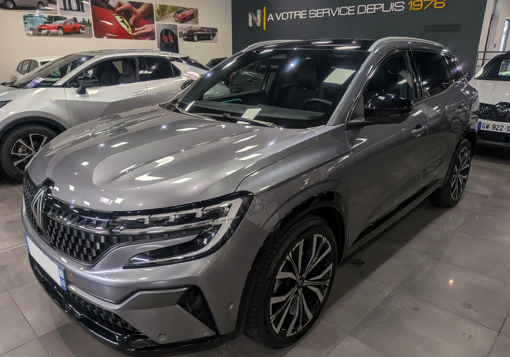 Renault Austral E-Tech hybride gris schiste vu en 3/4 avant droit dans un showroom moderne.