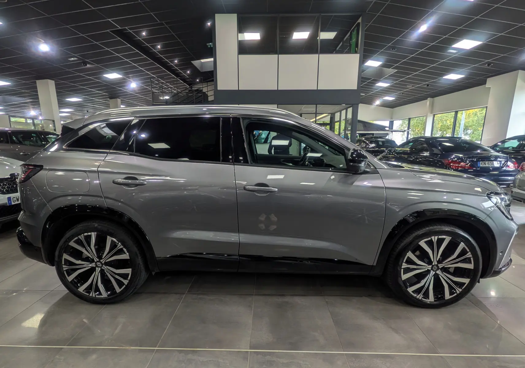 Profil côté gauche du Renault Austral E-TECH gris schiste 2024 en hybride, avec jantes alliage bicolores et vitres teintées.