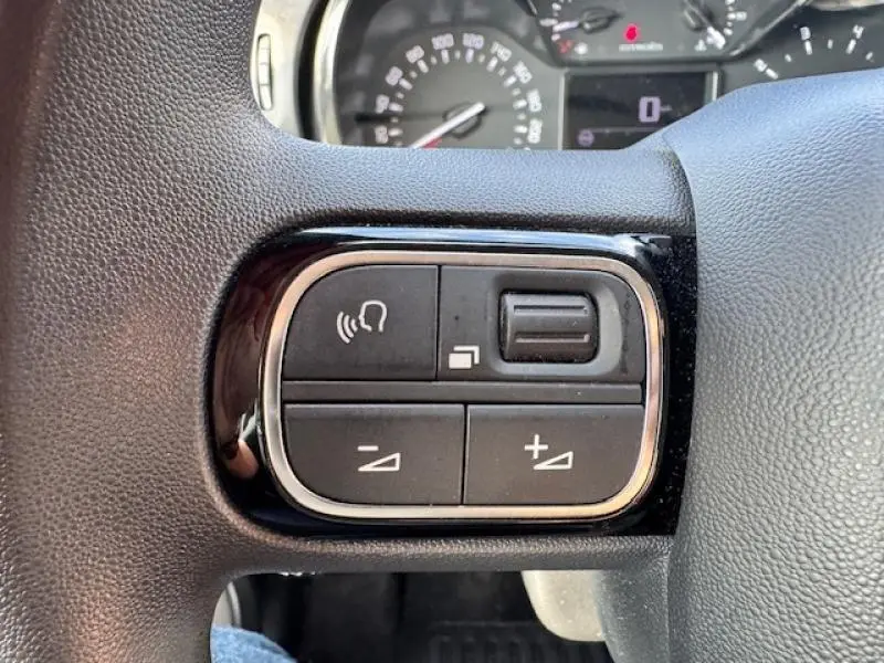 Gros plan sur les commandes vocales et volume au volant cuir de la Citroën C3 Shine 2021 finition Blanc Banquise.