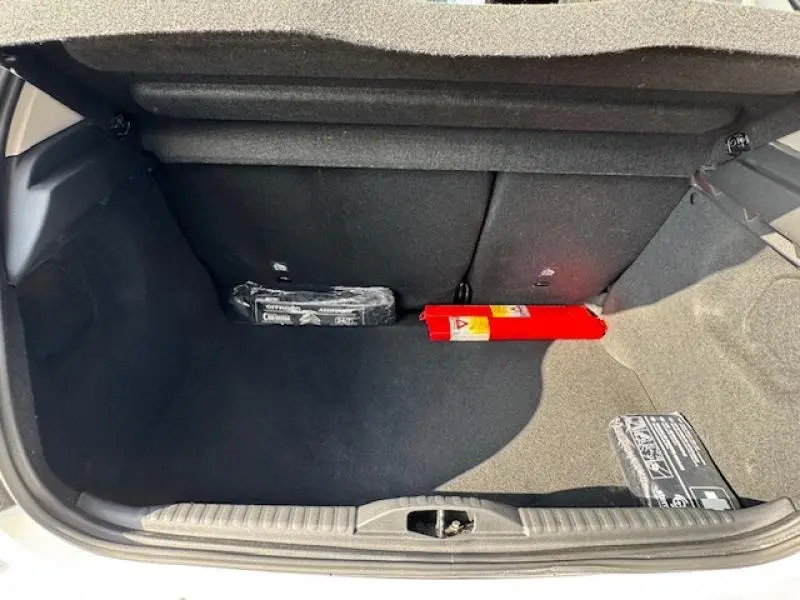 Coffre ouvert d'une Citroën C3 blanc Banquise, montrant un espace de rangement avec kit de sécurité et triangle rouge.